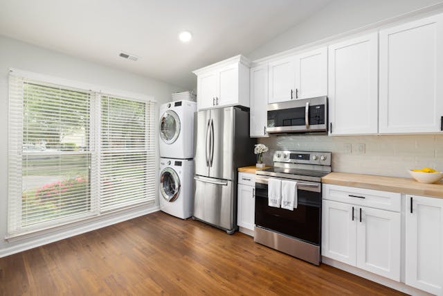 Furnished kitchen with wood floors, a microwave, strove, fridge, washer, and dryer.
